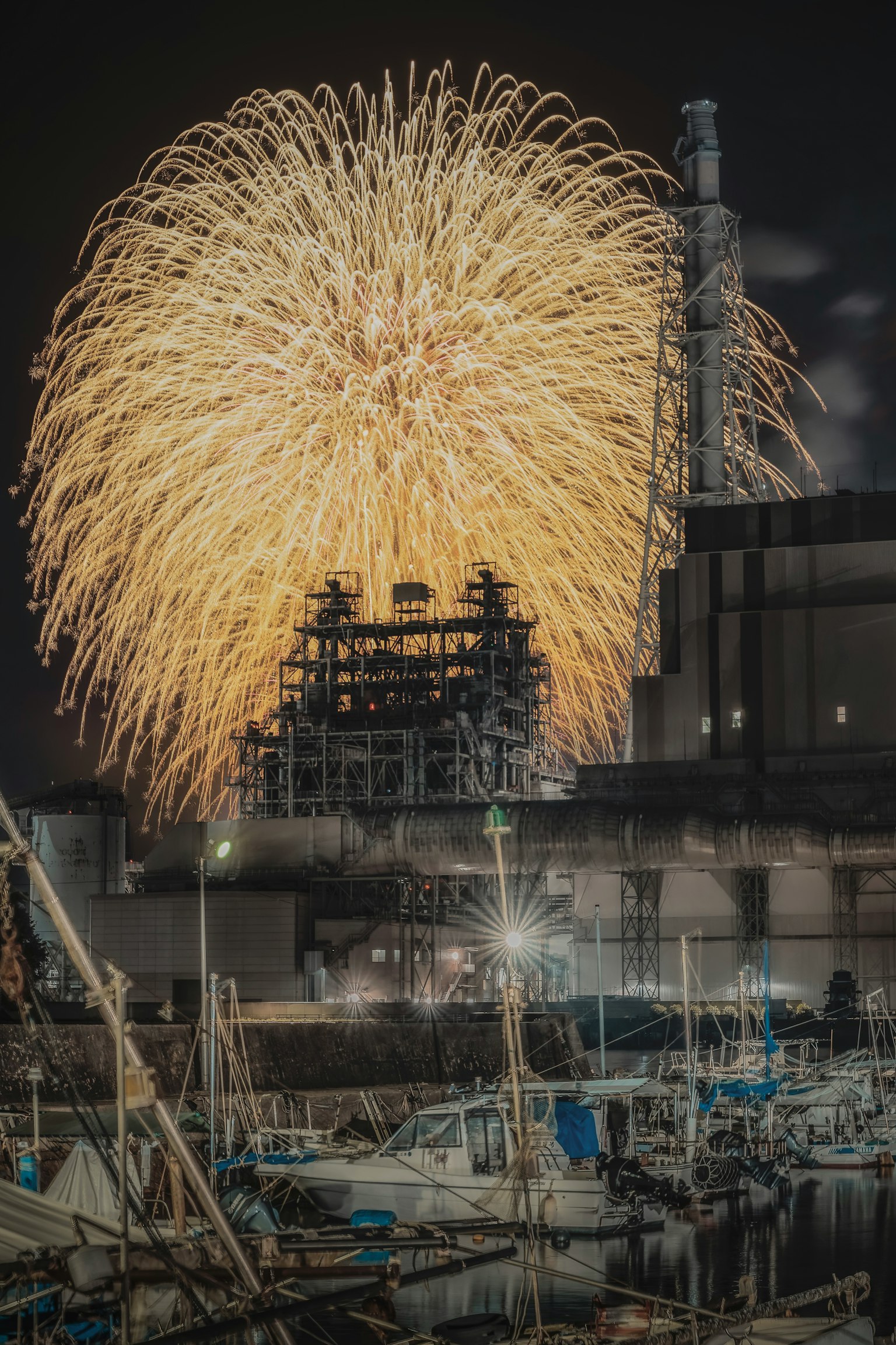 Fuegos artificiales dorados estallando en el cielo nocturno sobre un puerto
