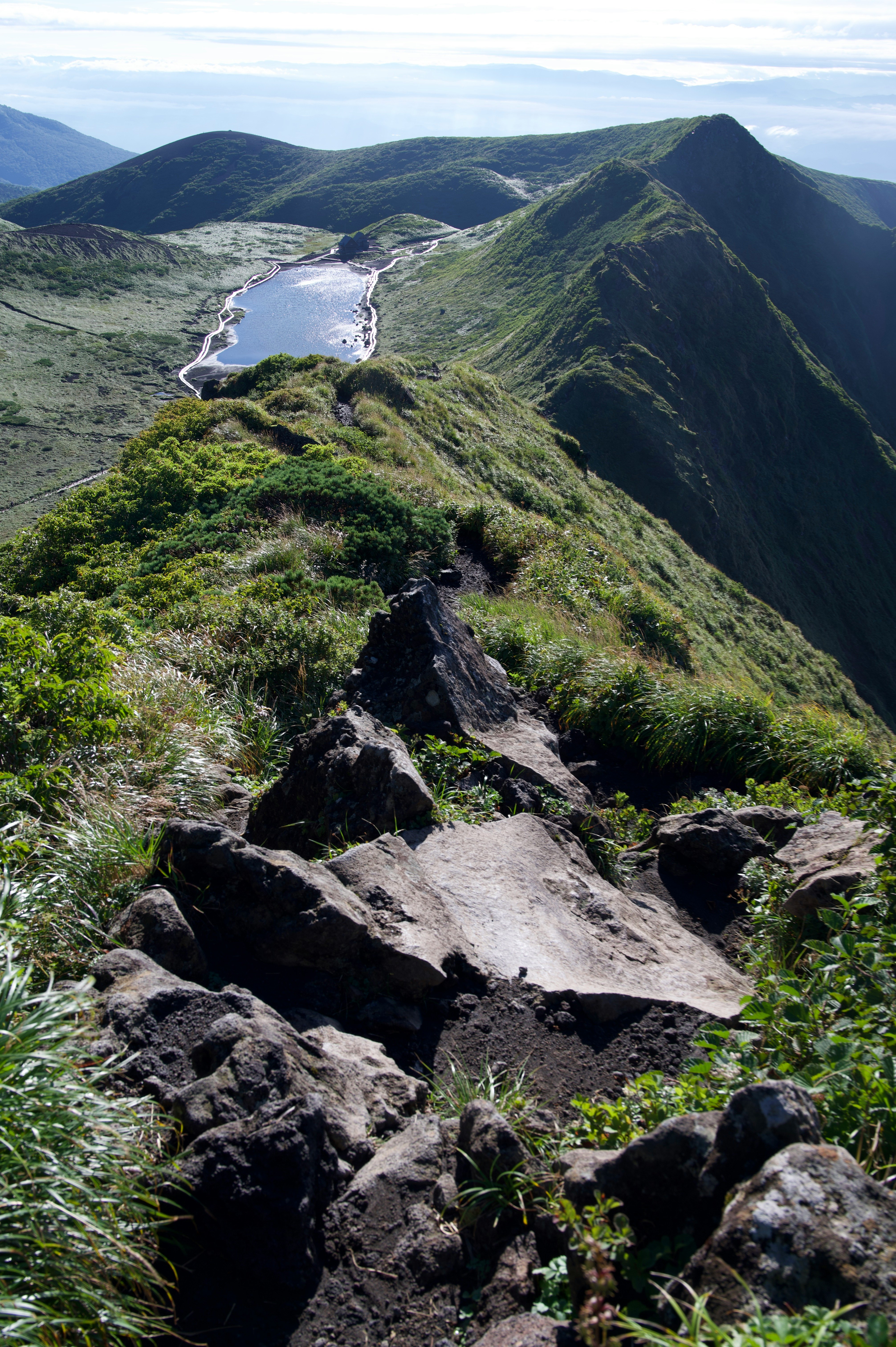 稜線から見下ろす緑の山並みと川の渓流