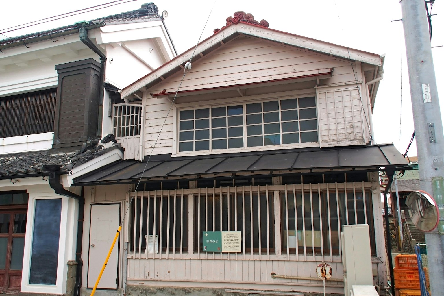 Exterior de un antiguo edificio japonés con ventanas de madera y una cerca de celosía