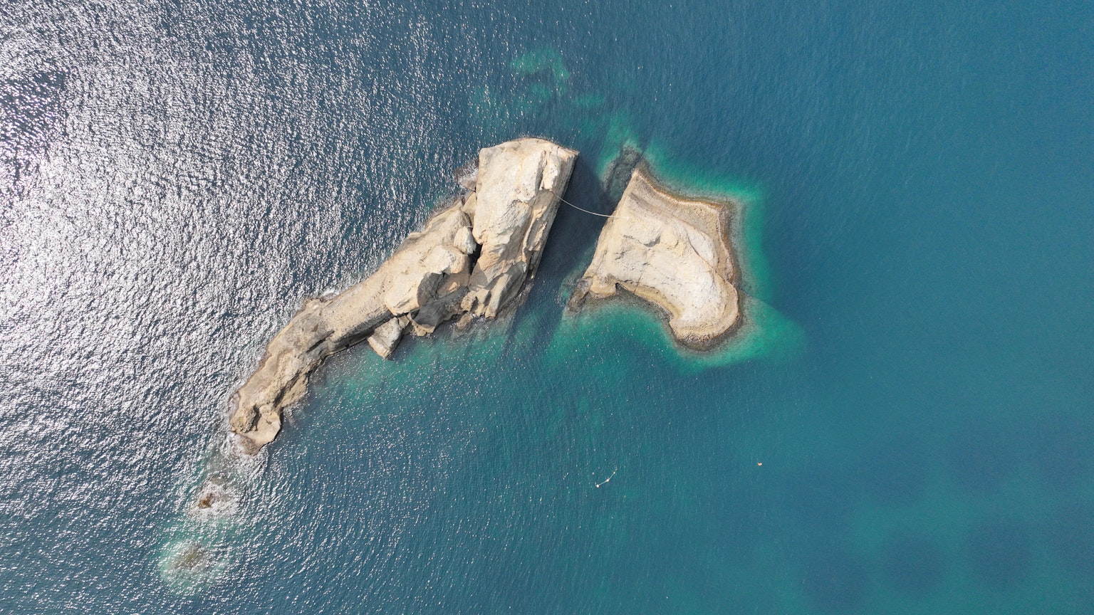 Pemandangan udara dari sebuah pulau kecil tak berpenghuni dikelilingi air biru