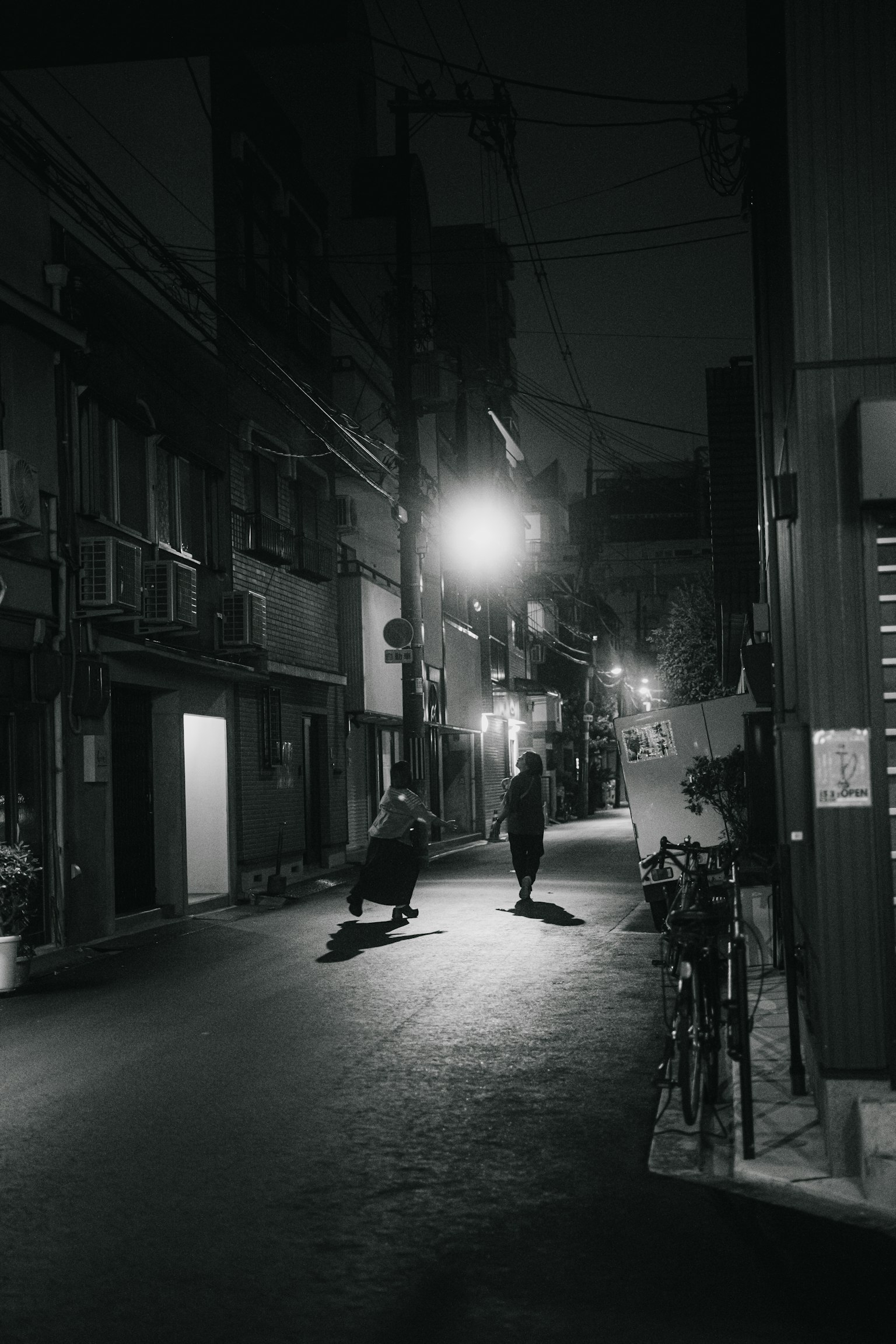 夜晚安静小巷中站着的两个人和路灯