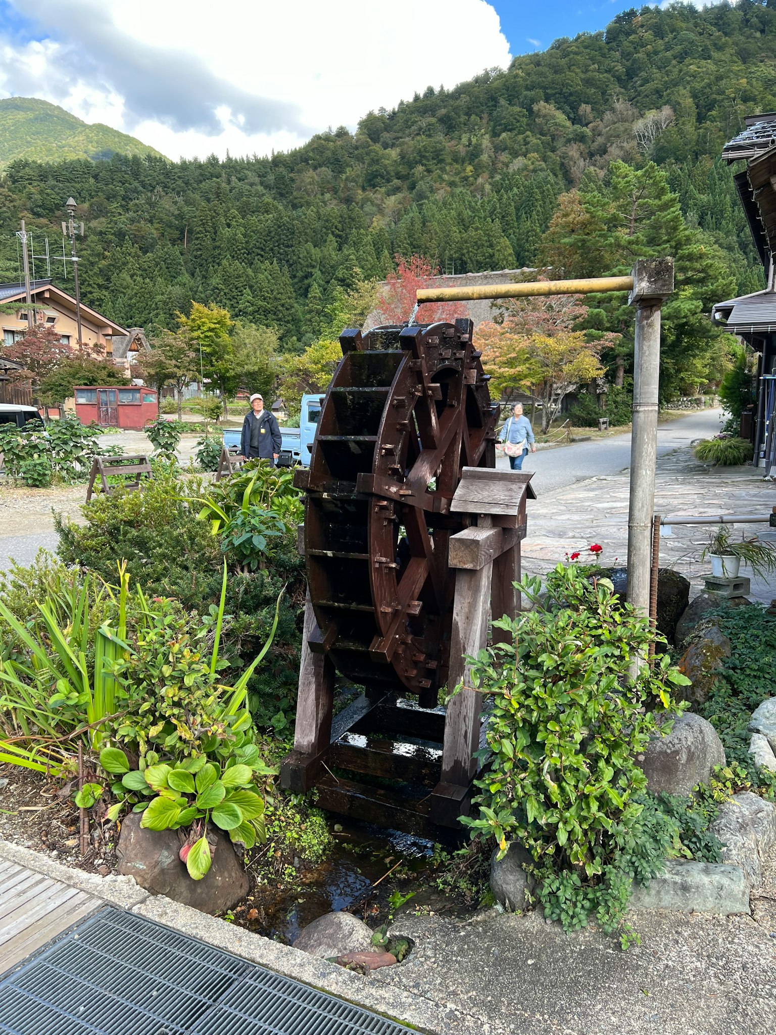 Water wheel surrounded by lush greenery and mountains