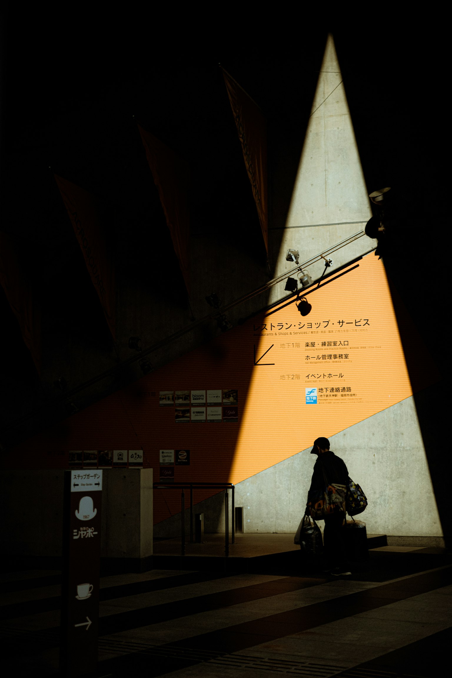 暗い背景にオレンジ色の三角形の壁と人が立っているシーン