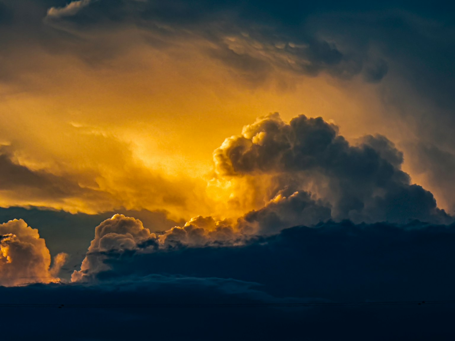 Dramatic sky with dark clouds illuminated by golden light