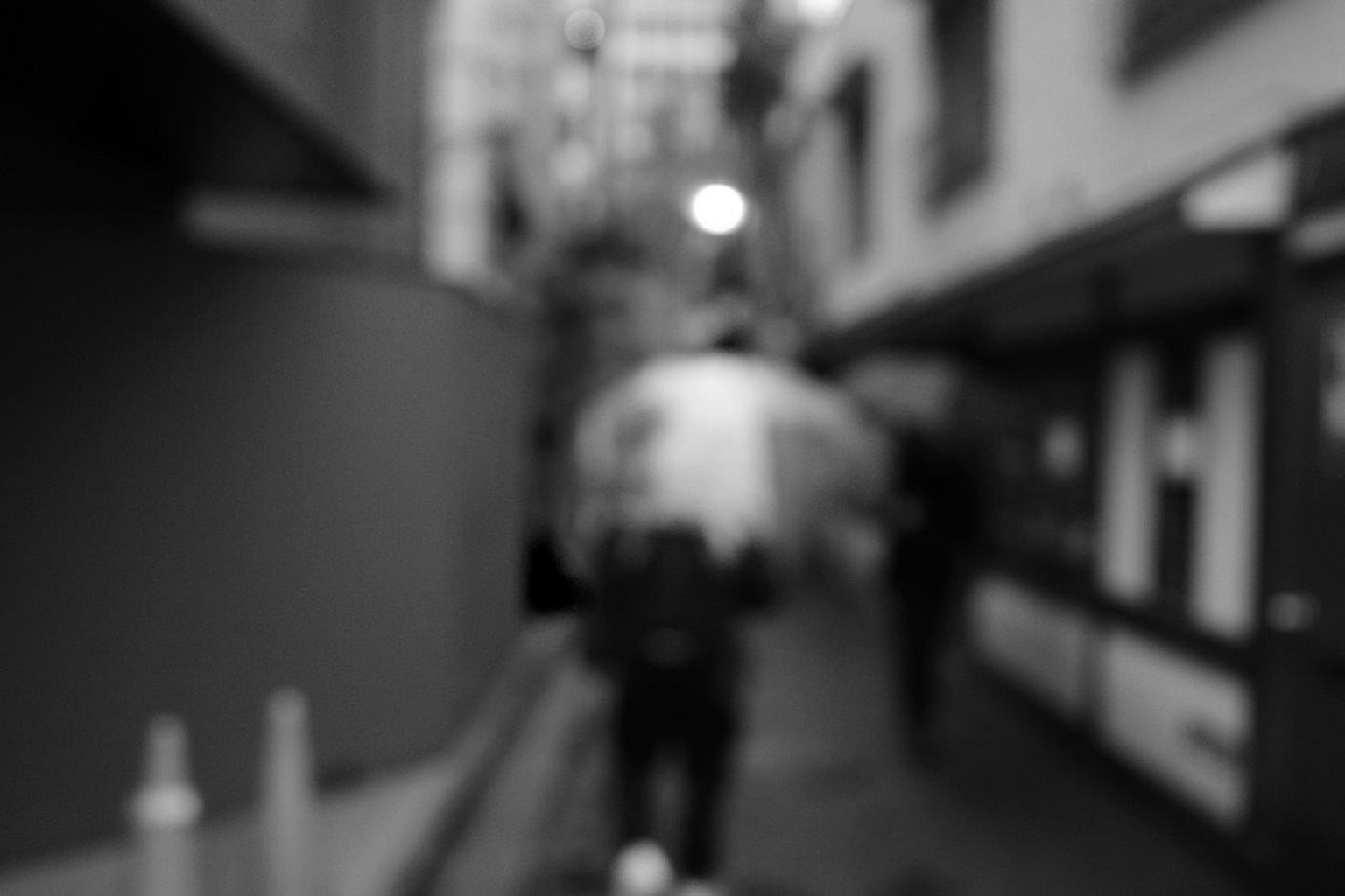 Silhouette einer Person mit einem Regenschirm in einer verschwommenen Gasse
