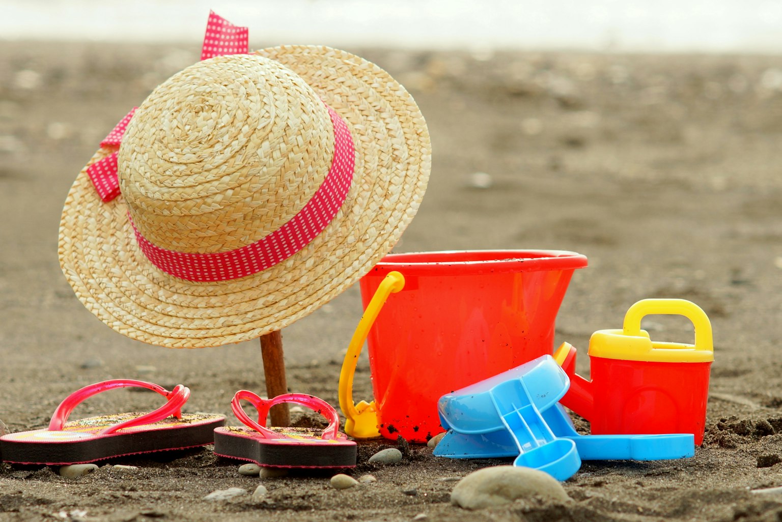 Straw hat and colorful beach toys on the sand