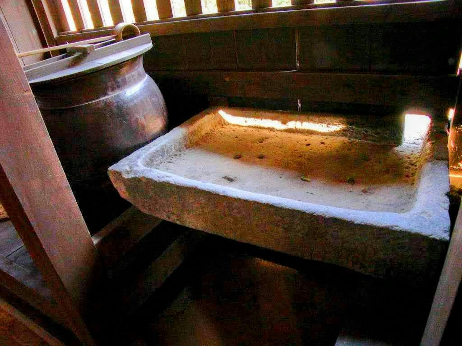 Un ancien intérieur avec un bassin en pierre et un pot en céramique