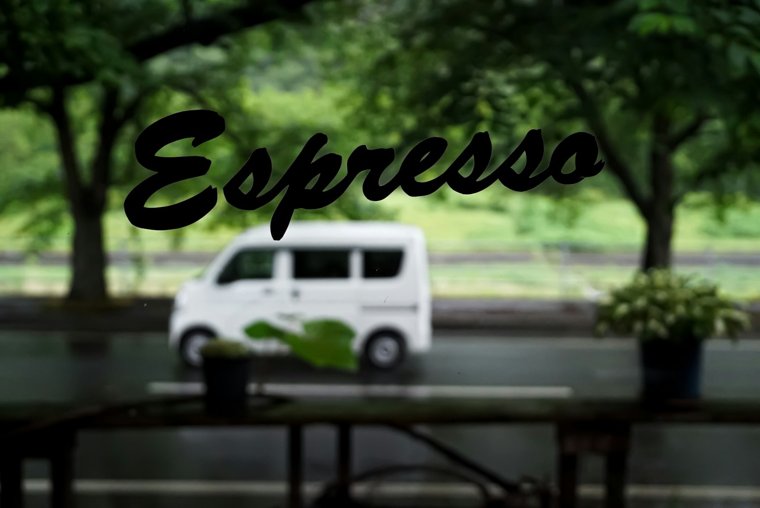 Vue à travers une fenêtre de café avec le mot Espresso et une camionnette blanche qui passe