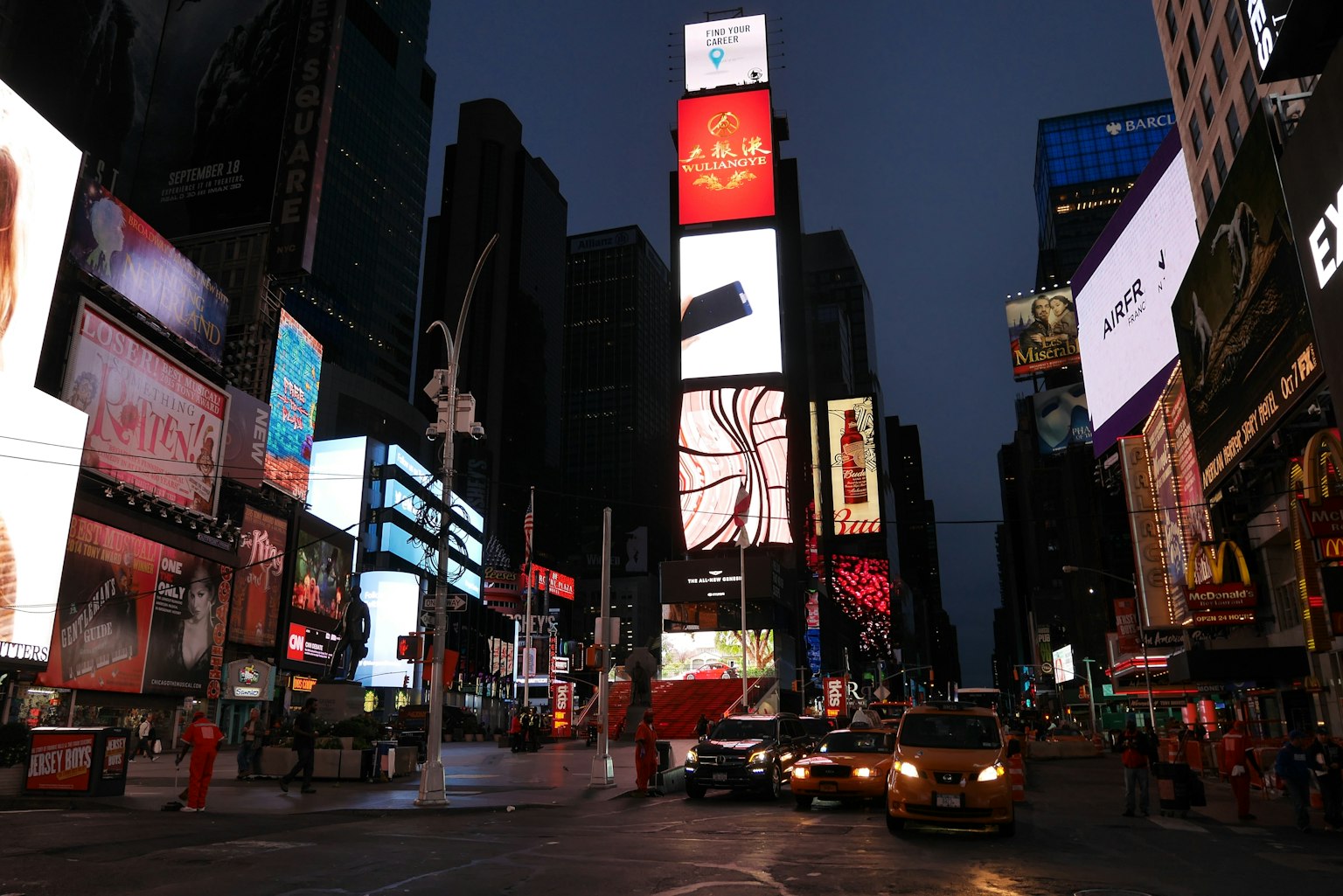 Times Square de noche con letreros luminosos y vehículos