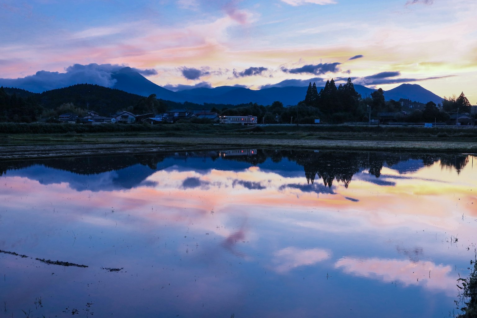 Pemandangan indah sawah yang mencerminkan matahari terbenam yang indah dan gunung