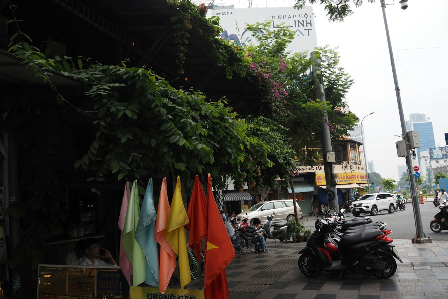 Drapeaux colorés alignés à un coin de rue verdoyant avec des motos
