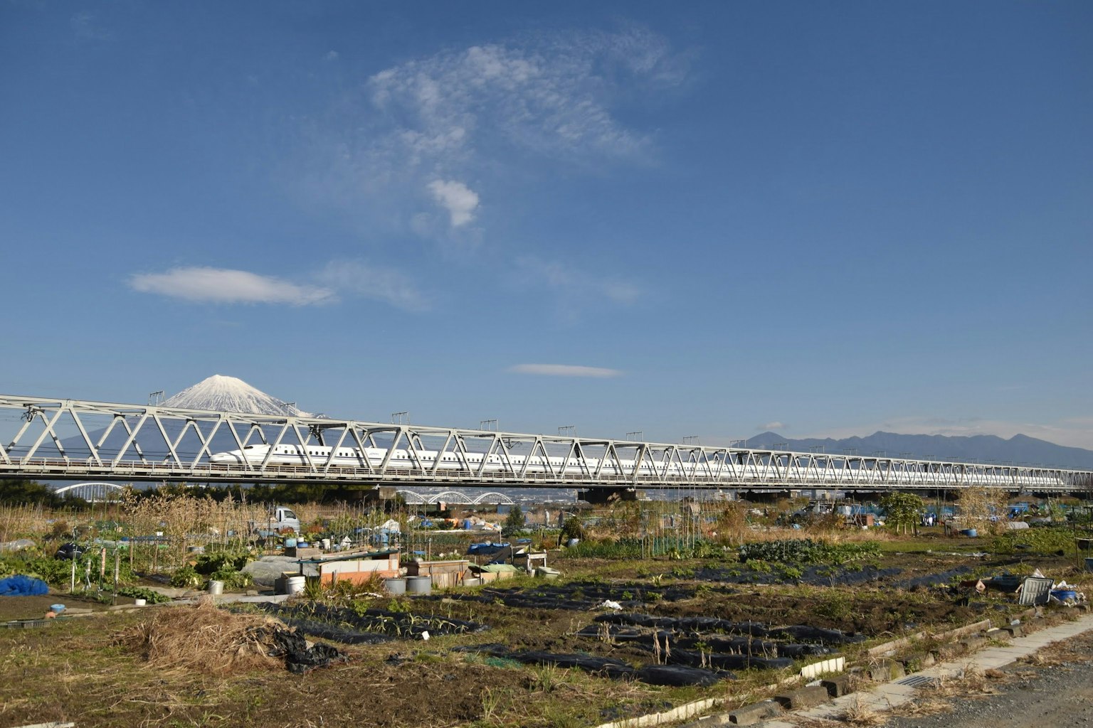 Jembatan besi putih dengan Gunung Fuji di latar belakang dan pemandangan sekitar