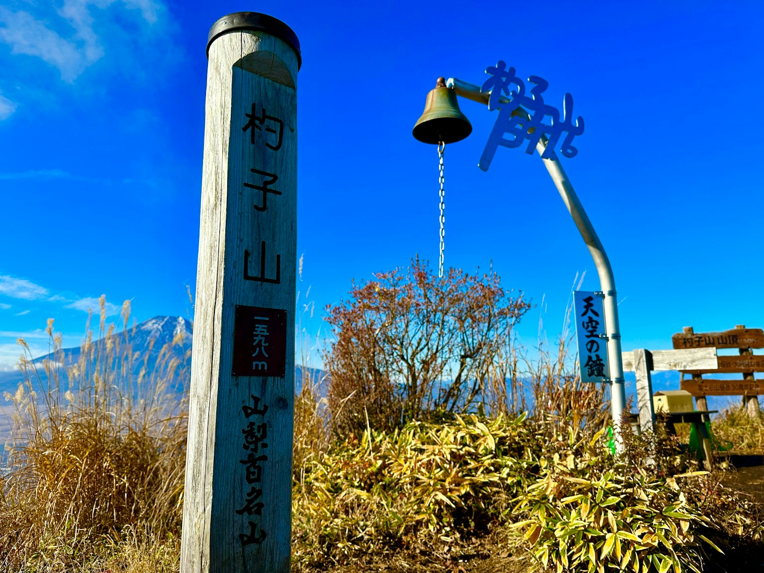 Sign and bell at the mountain summit with blue sky