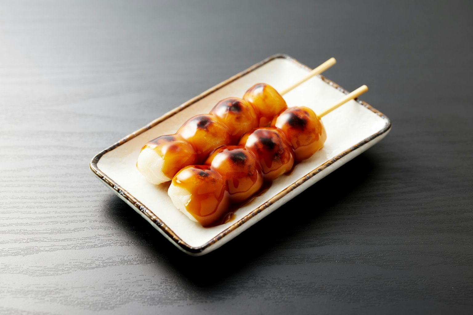 Grilled sweet dumplings on skewers served on a white plate