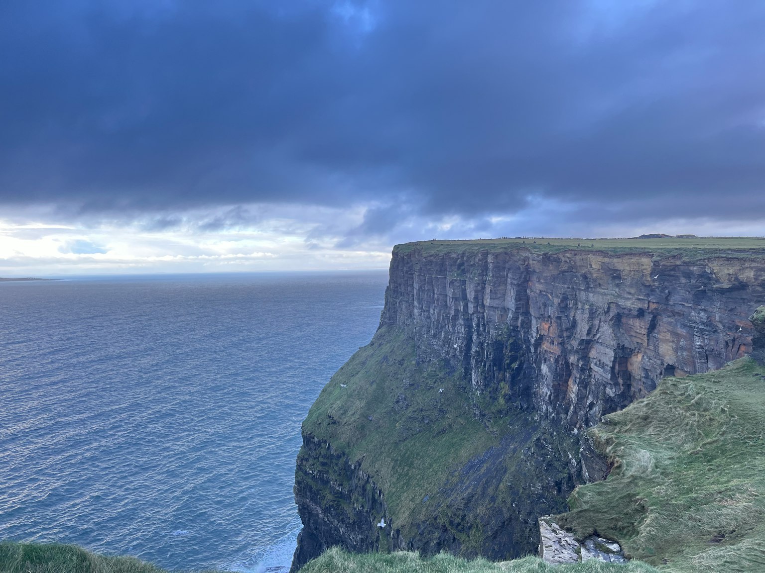 Dramatic cliff overlooking the ocean with a blue sky and clouds