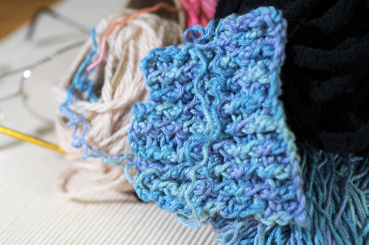 Bild mit einer Mischung aus Garnmaterialien und einem blauen Strickstück