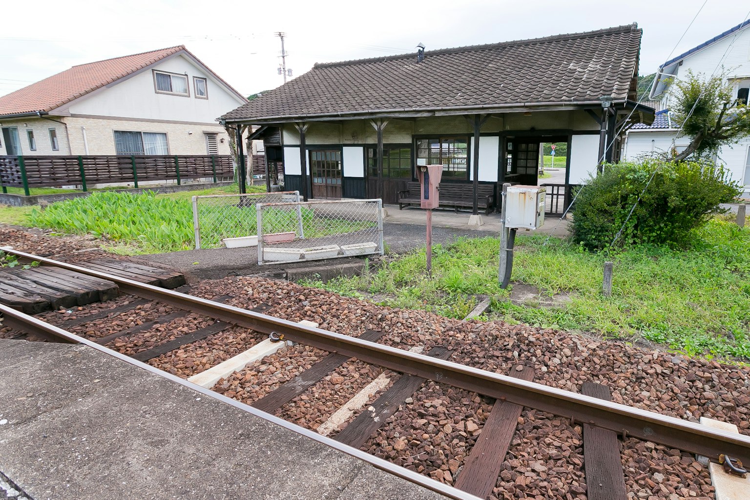 Vue d'une vieille gare avec des voies ferrées et de l'herbe envahissante