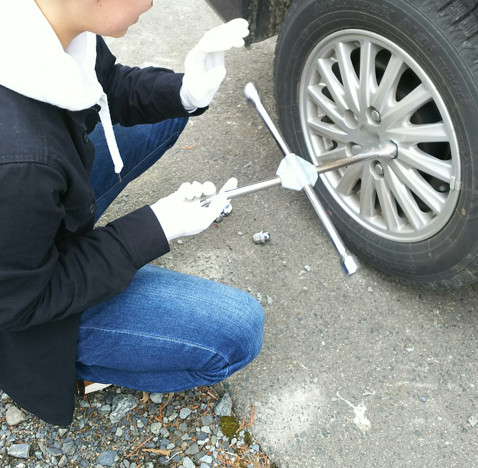 Eine Person, die einen Autoreifen auf einer Kiesoberfläche wechselt