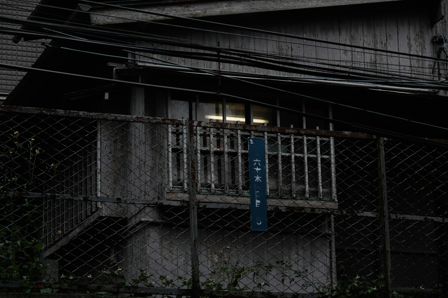 Vista exterior de una ventana con un letrero azul sobre un fondo oscuro