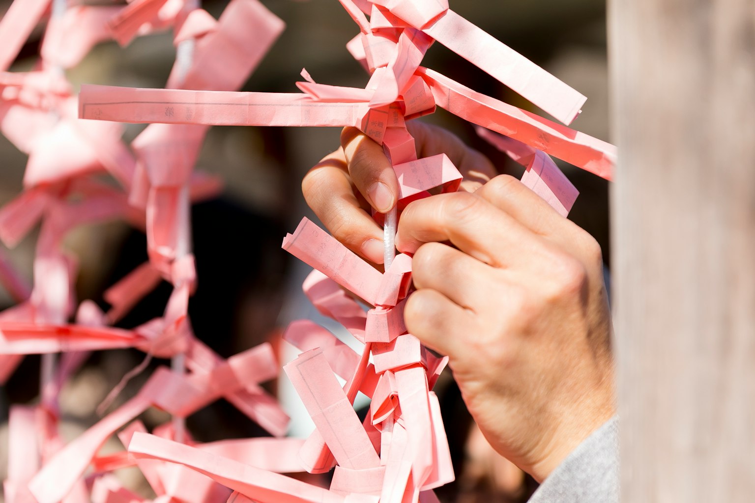 Close-up of hands tying pink paper strips