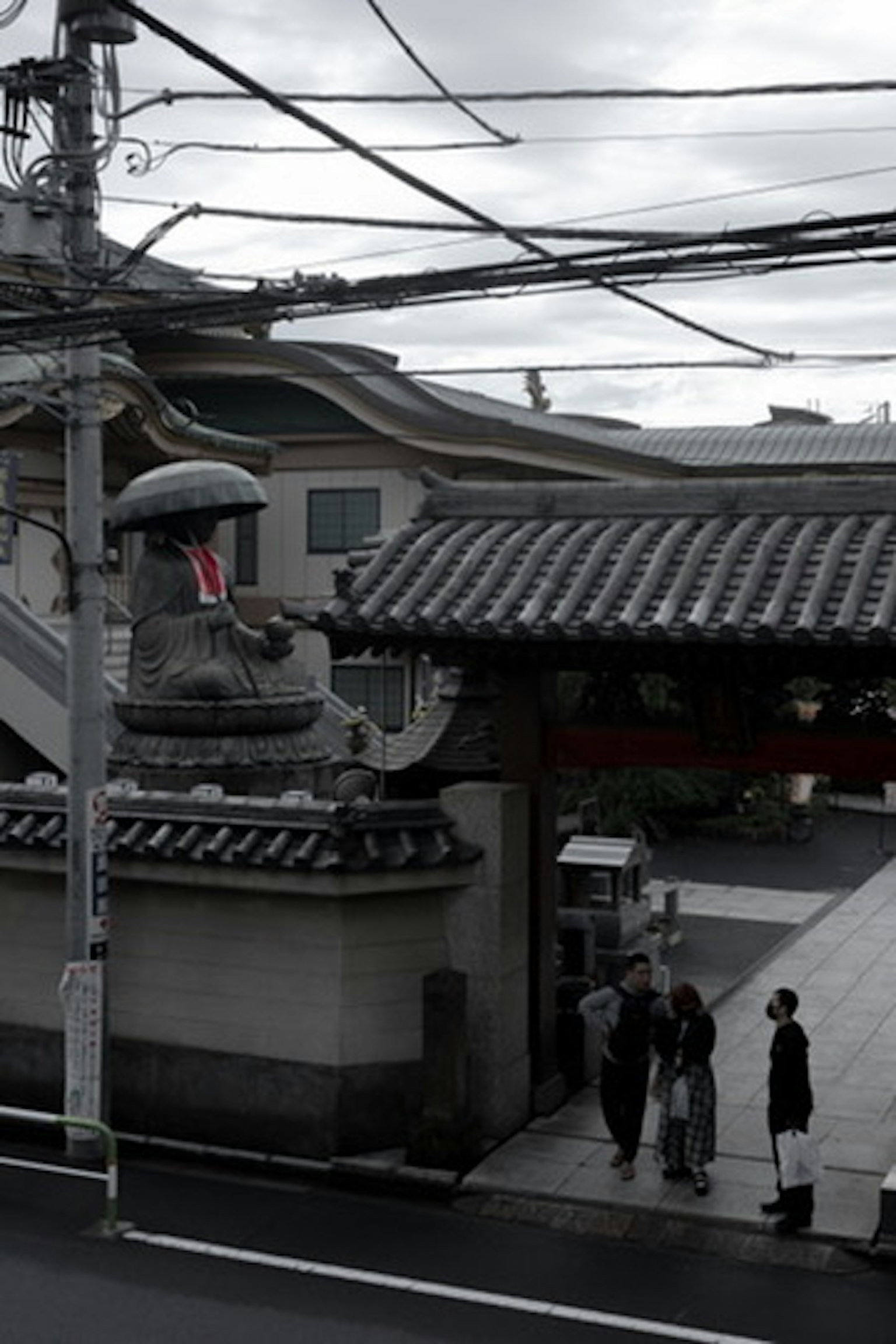 人们站在日本街道场景的屋顶门前，周围有电线