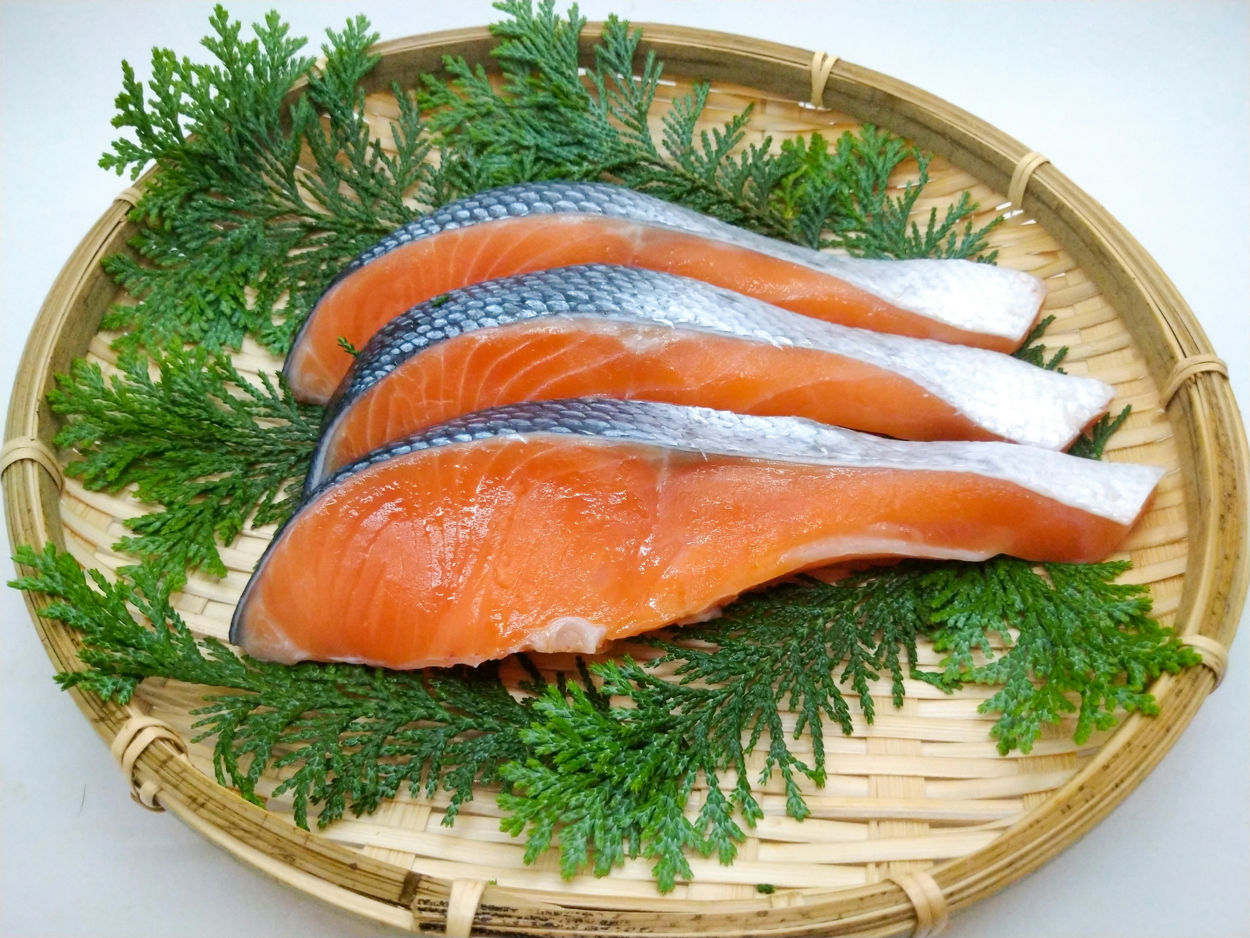 竹籃裡擺放的鮭魚片與綠色紫蘇