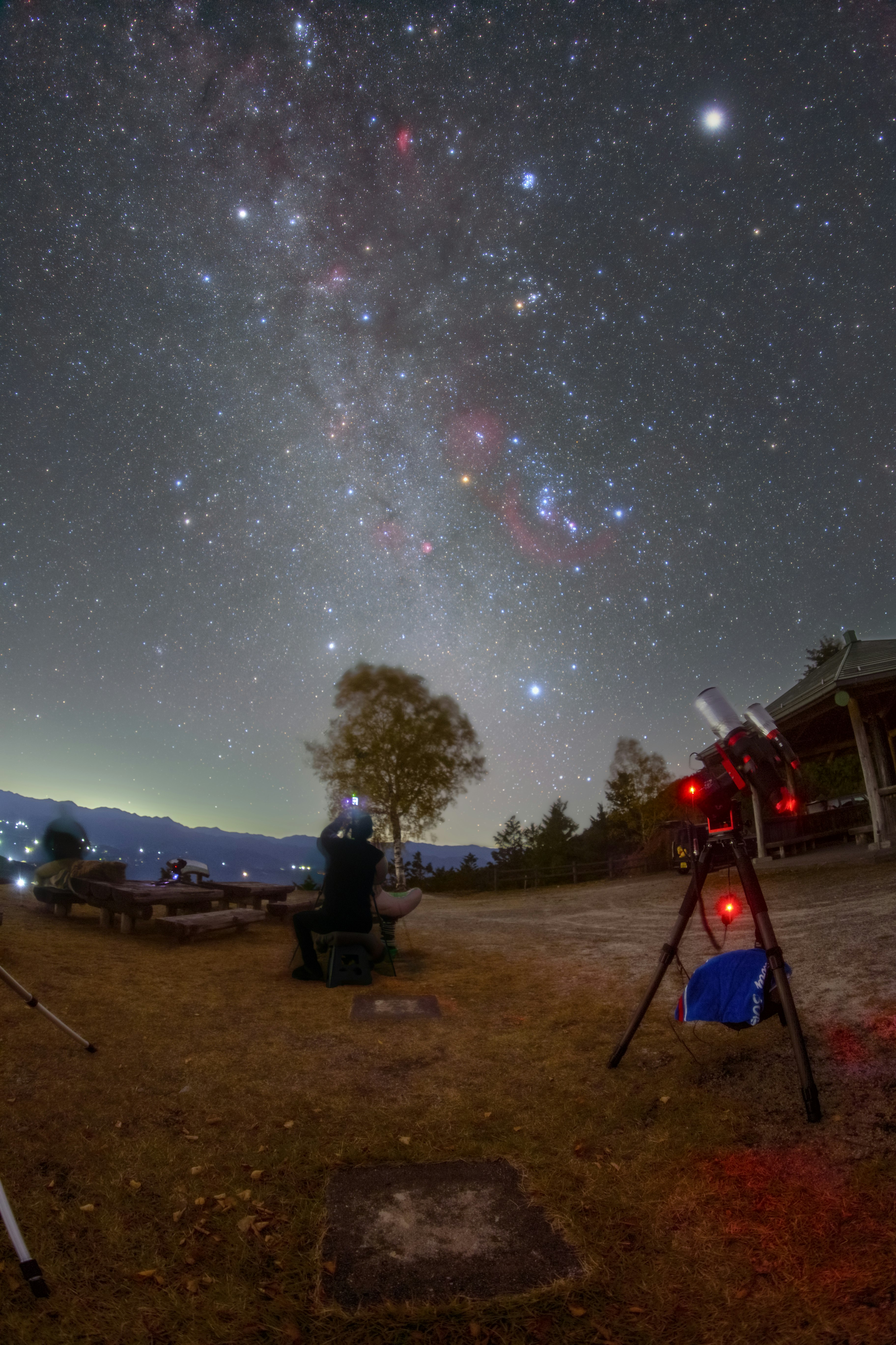 天体望遠鏡で星空を観測するキャンプ場の夜景