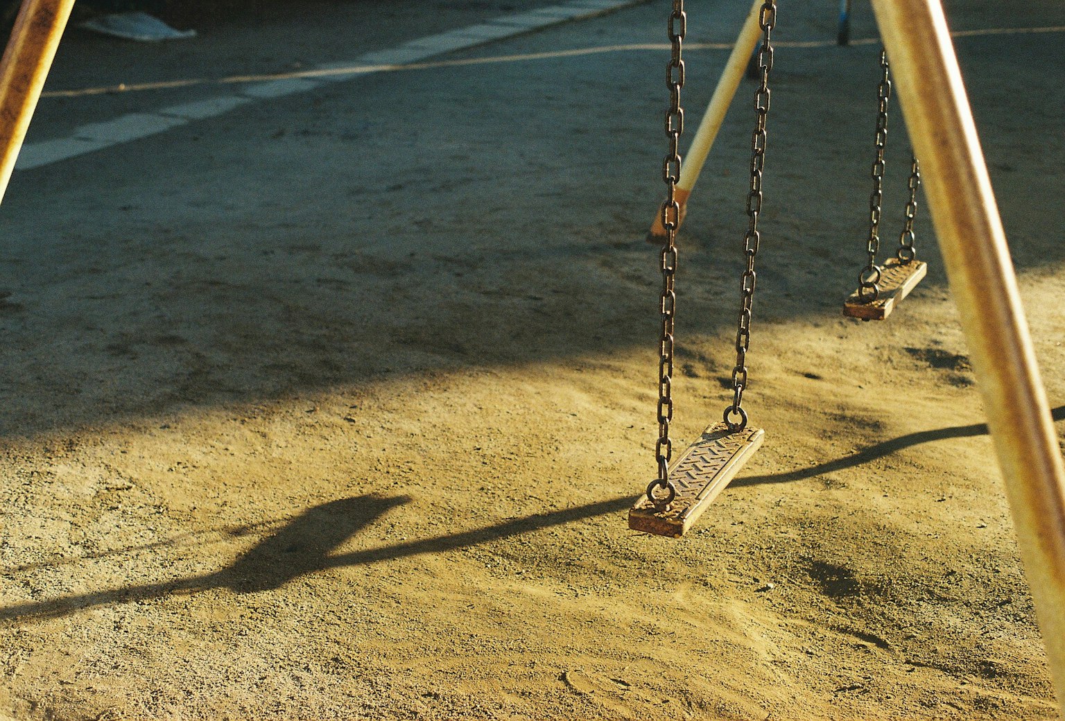 Evening scene featuring the shadow of a playground swing