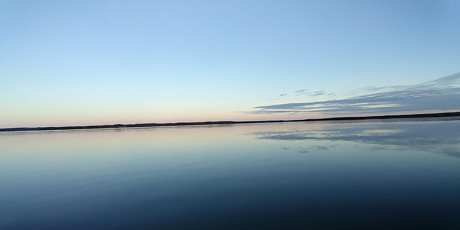 พื้นผิวน้ำสงบสะท้อนท้องฟ้าสีฟ้าสดใส