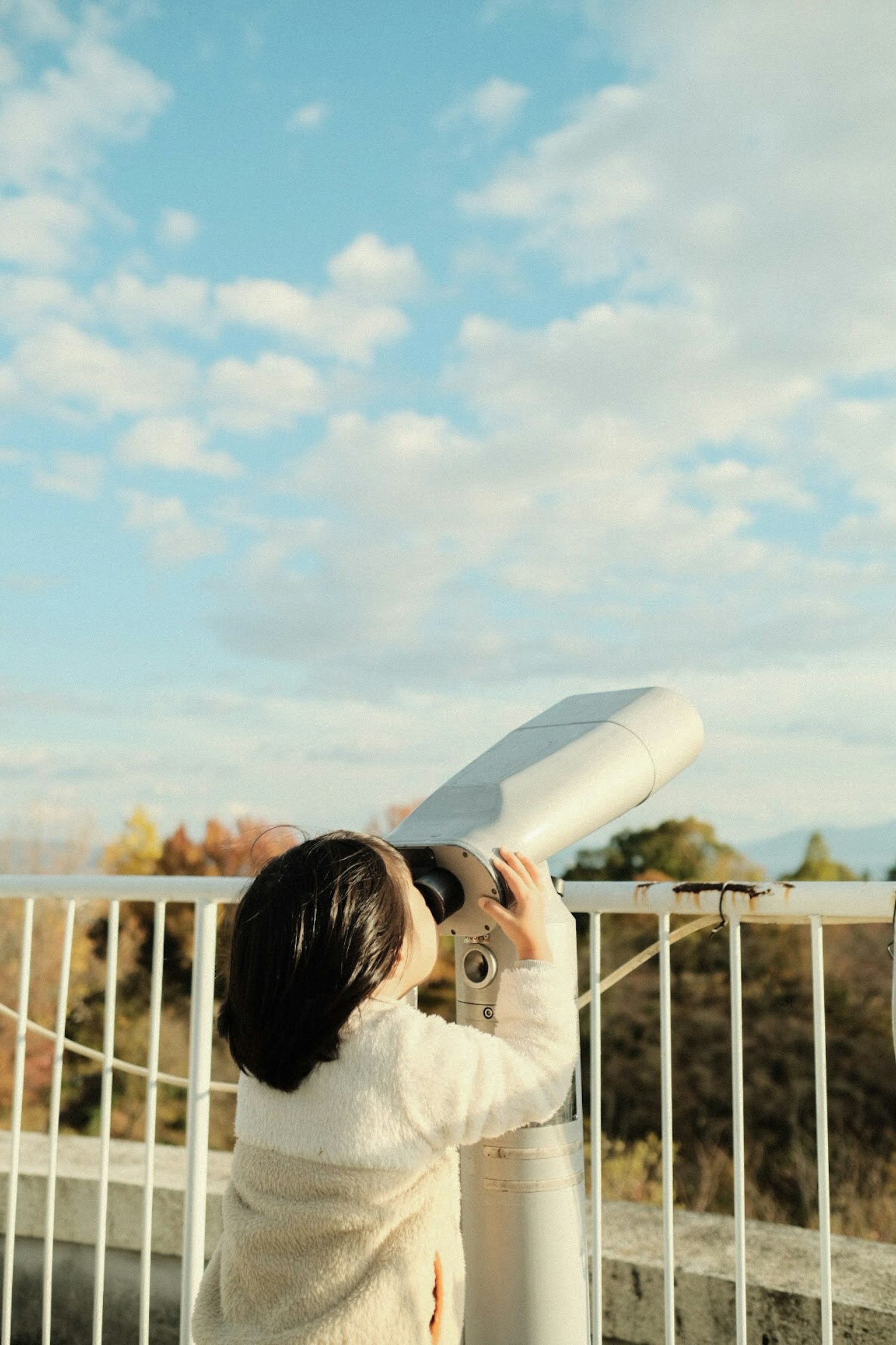 子供が望遠鏡を使って空を見上げている風景
