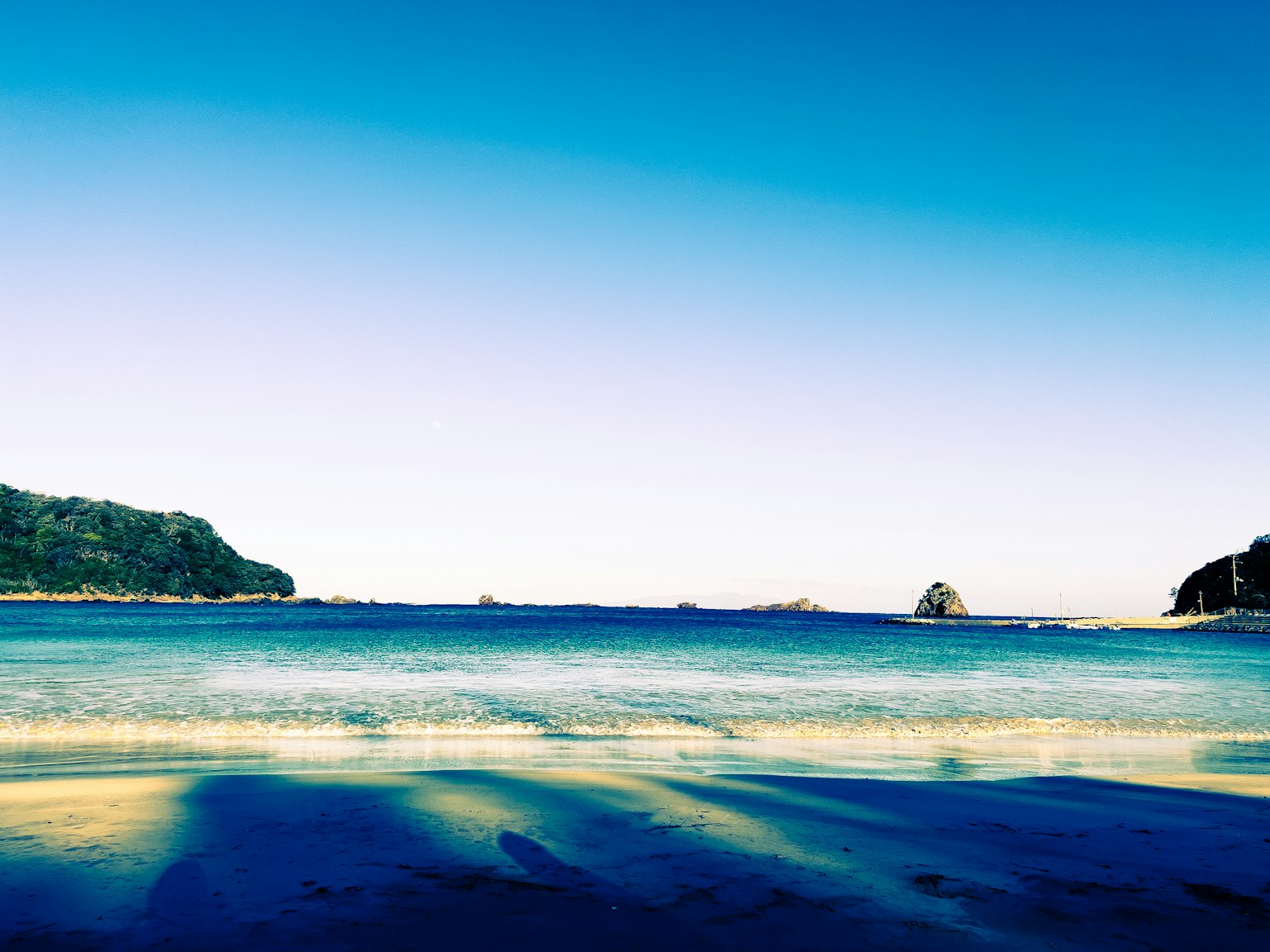 Pemandangan indah langit biru dan laut dengan pantai berpasir dan batu-batu tersebar