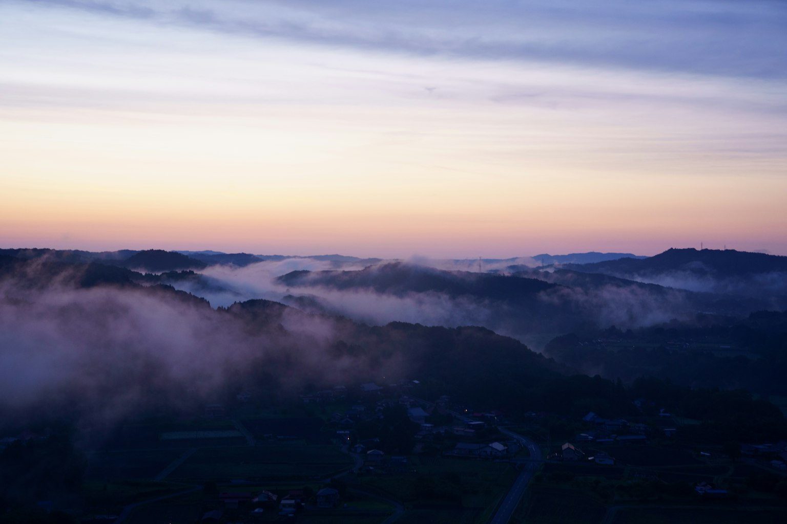 Colline avvolte nella nebbia al tramonto con un cielo colorato