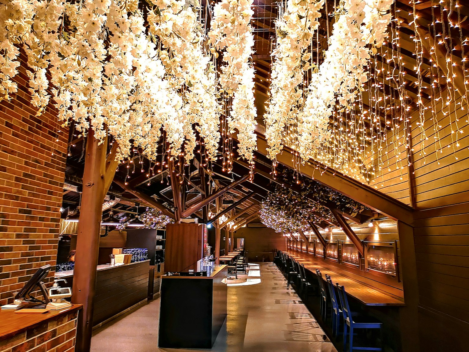Interno di un ristorante con fiori e luci appese al soffitto