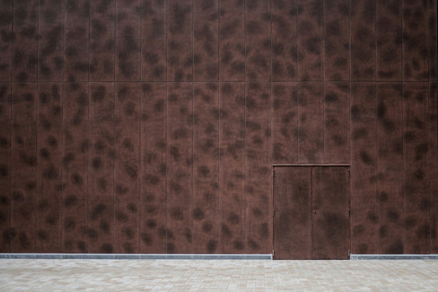 Modern building exterior with a small door on a brown wall
