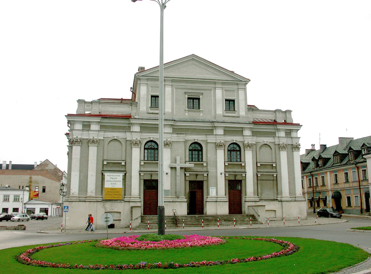 Facade of a classical style theater with a flowerbed and streetlamp in a plaza