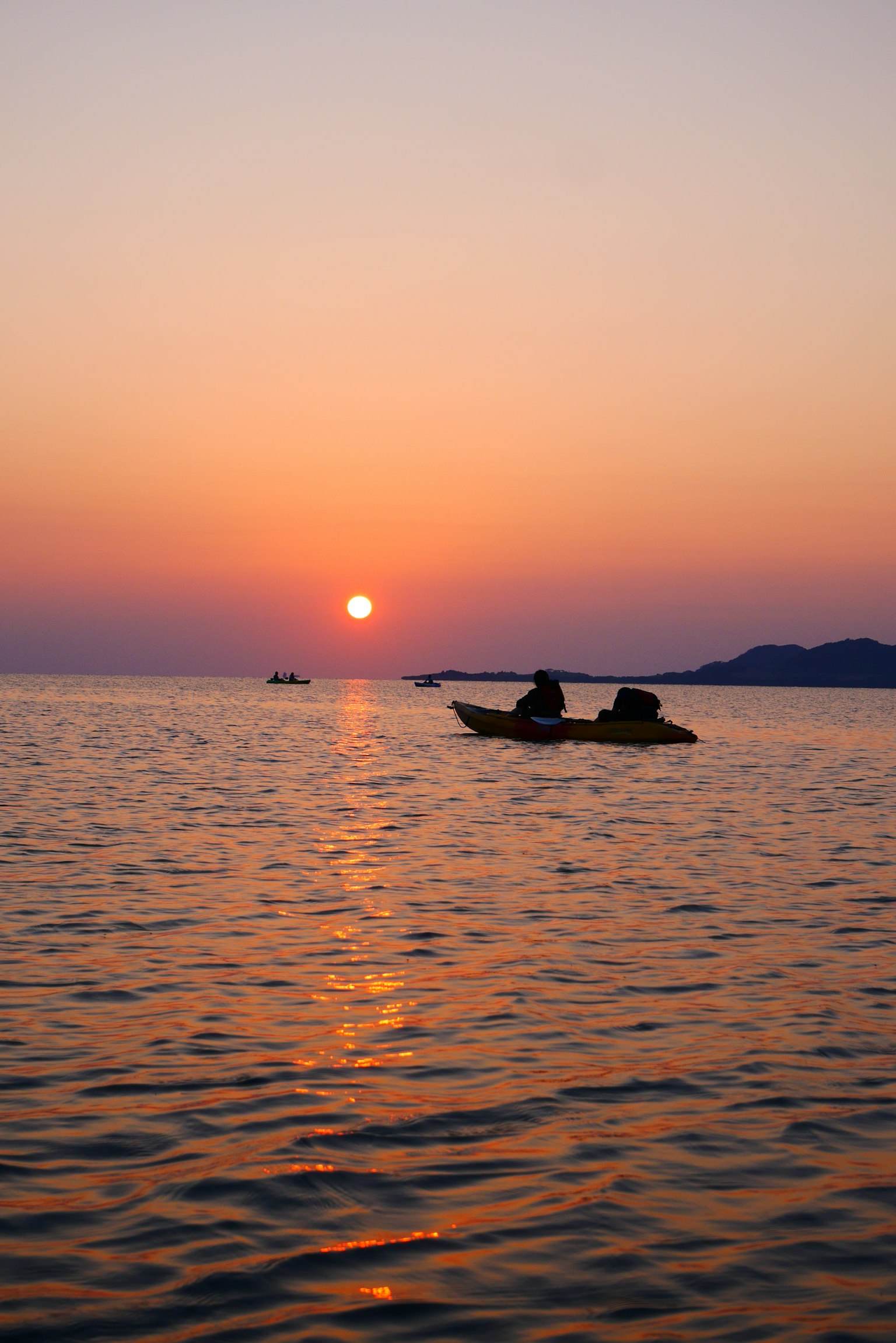 Bóng silhouette của hai người chèo thuyền kayak trên biển lúc hoàng hôn