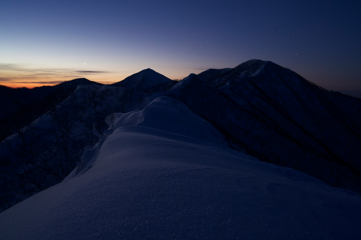 Cresta de montaña cubierta de nieve bajo un cielo crepuscular