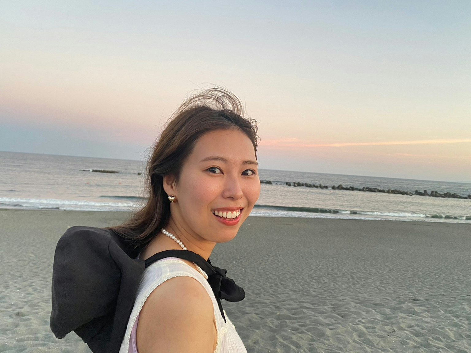 Donna sorridente sulla spiaggia con cielo al tramonto