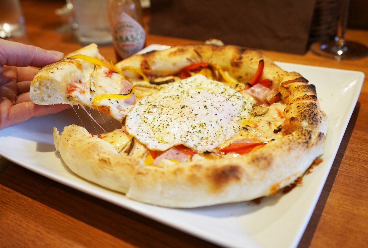 Main tenant une pizza fromagère avec des légumes frais