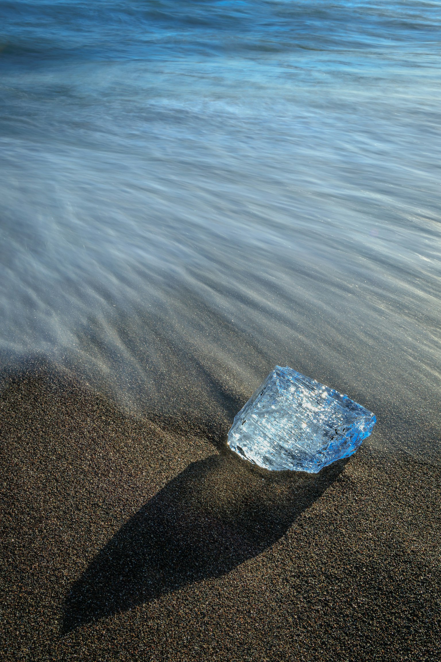 沙灘上的透明冰塊與流動的海浪