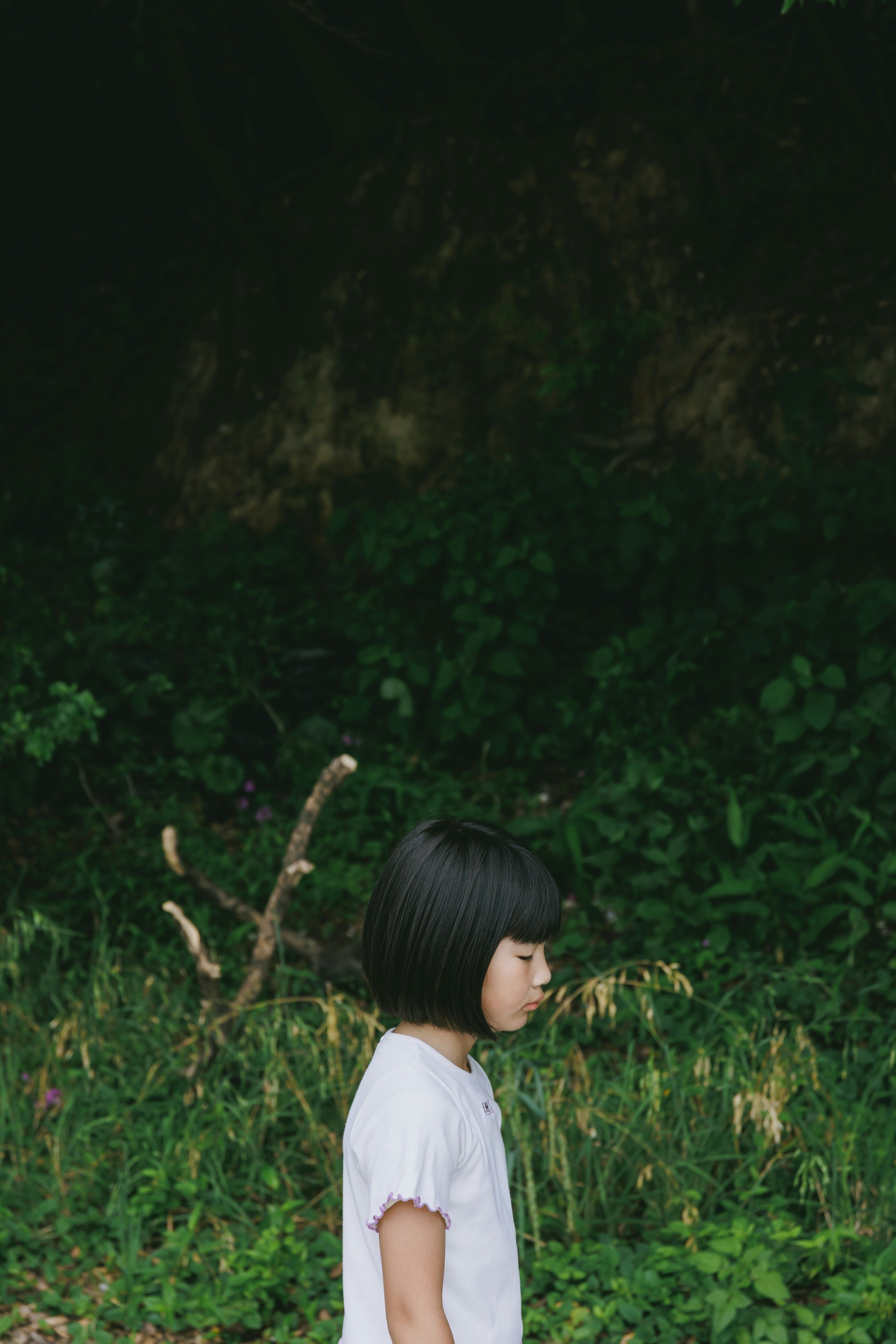 草むらの中で横を向く子どもの後ろ姿
