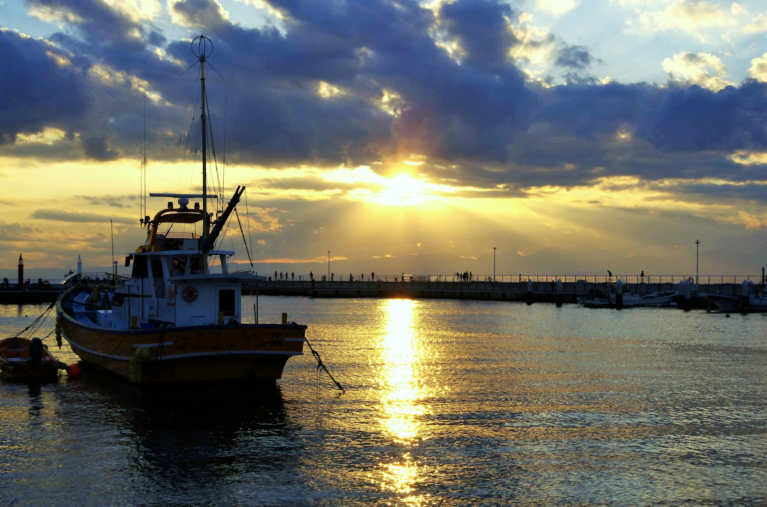 Peschereccio ancorato in un porto con il tramonto che si riflette sull'acqua