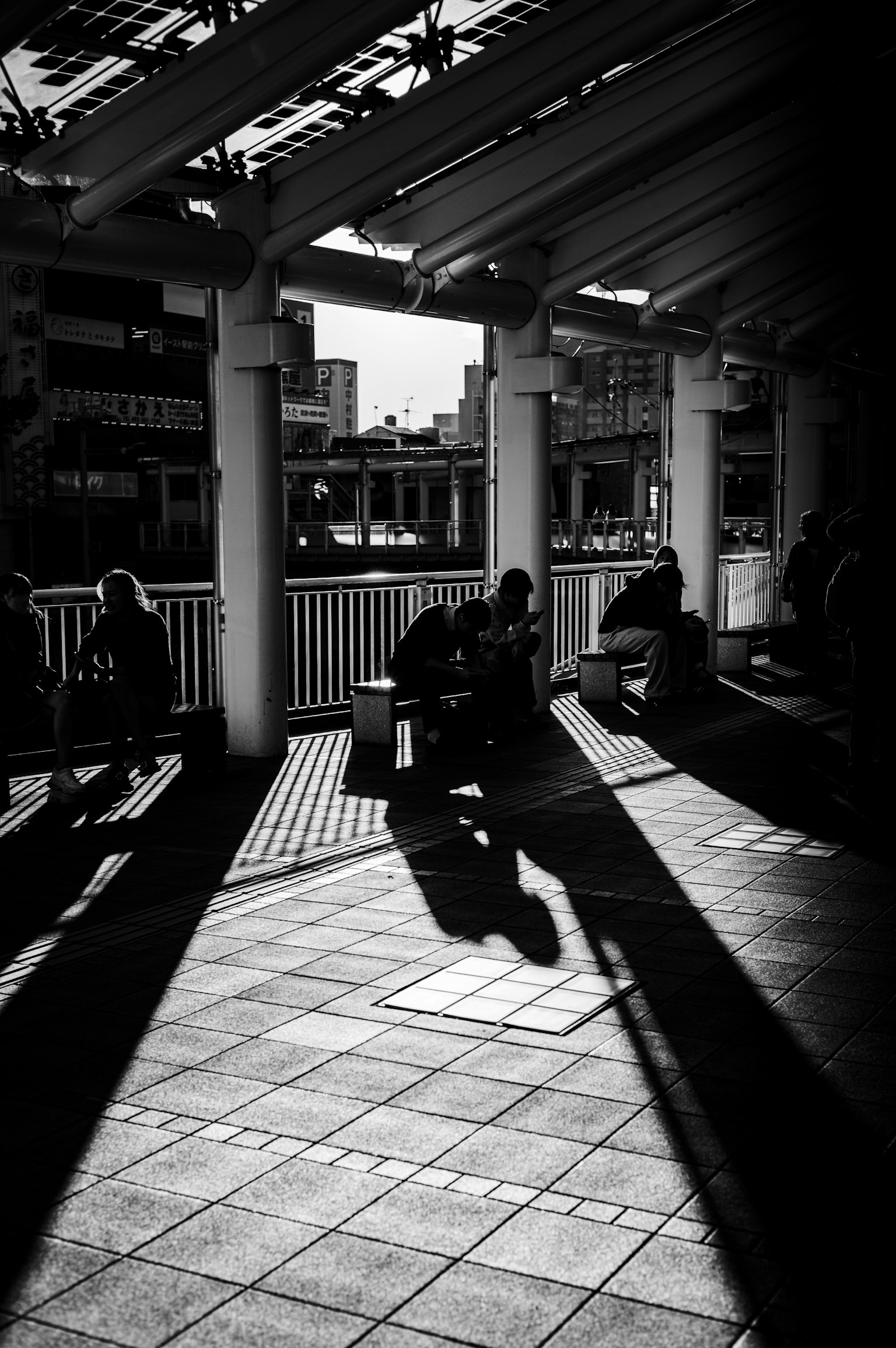 Área de espera al aire libre con sombras en blanco y negro que se cruzan