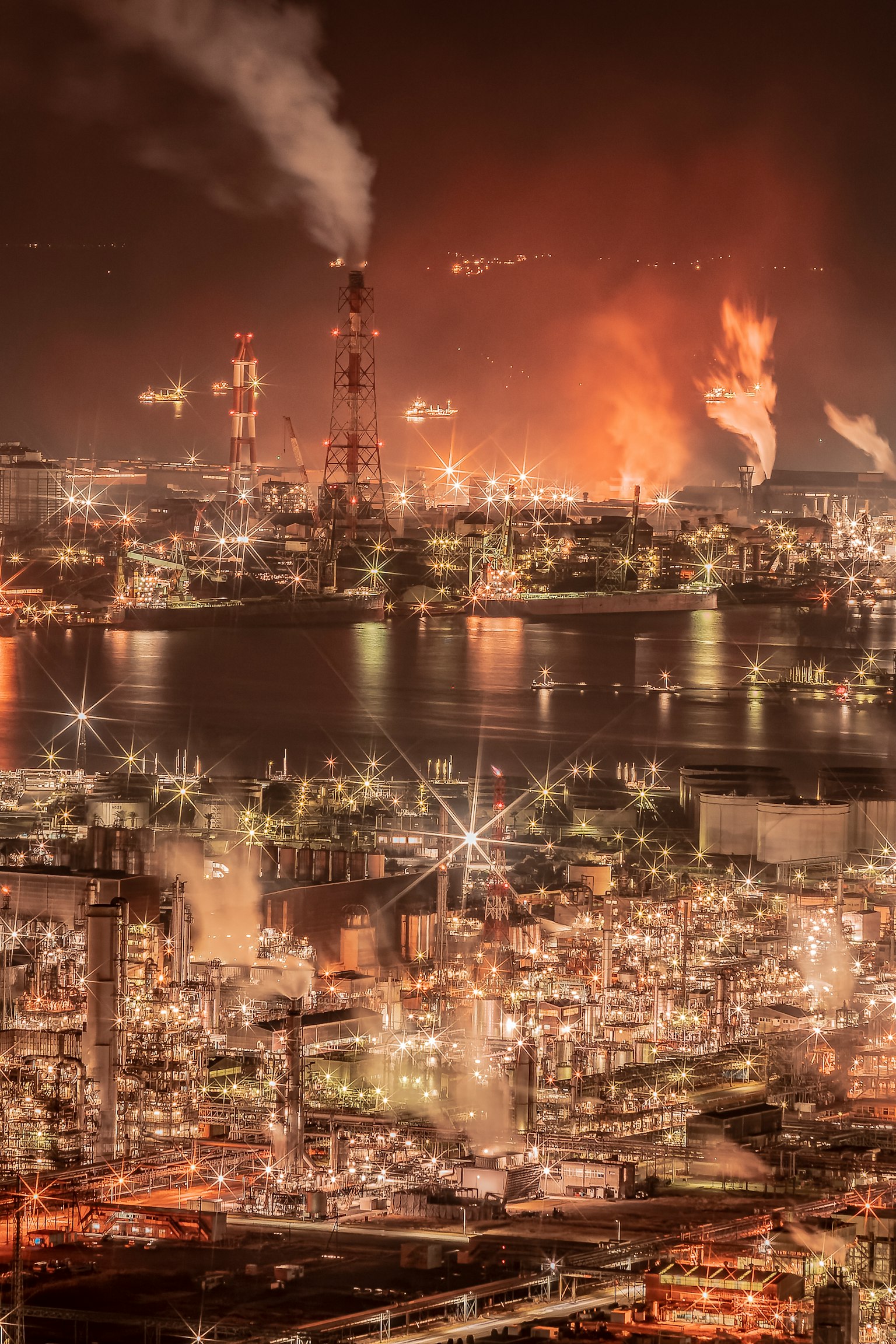 Industrial area illuminated at night with smoke stacks and flames