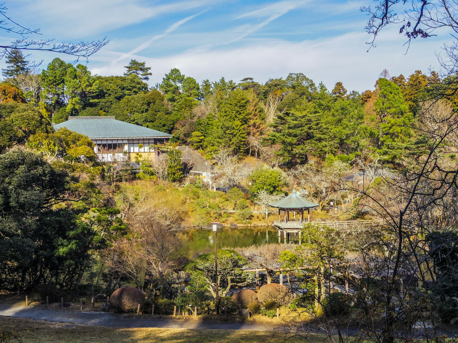 Vista escénica de un edificio japonés tradicional y un estanque en un parque exuberante