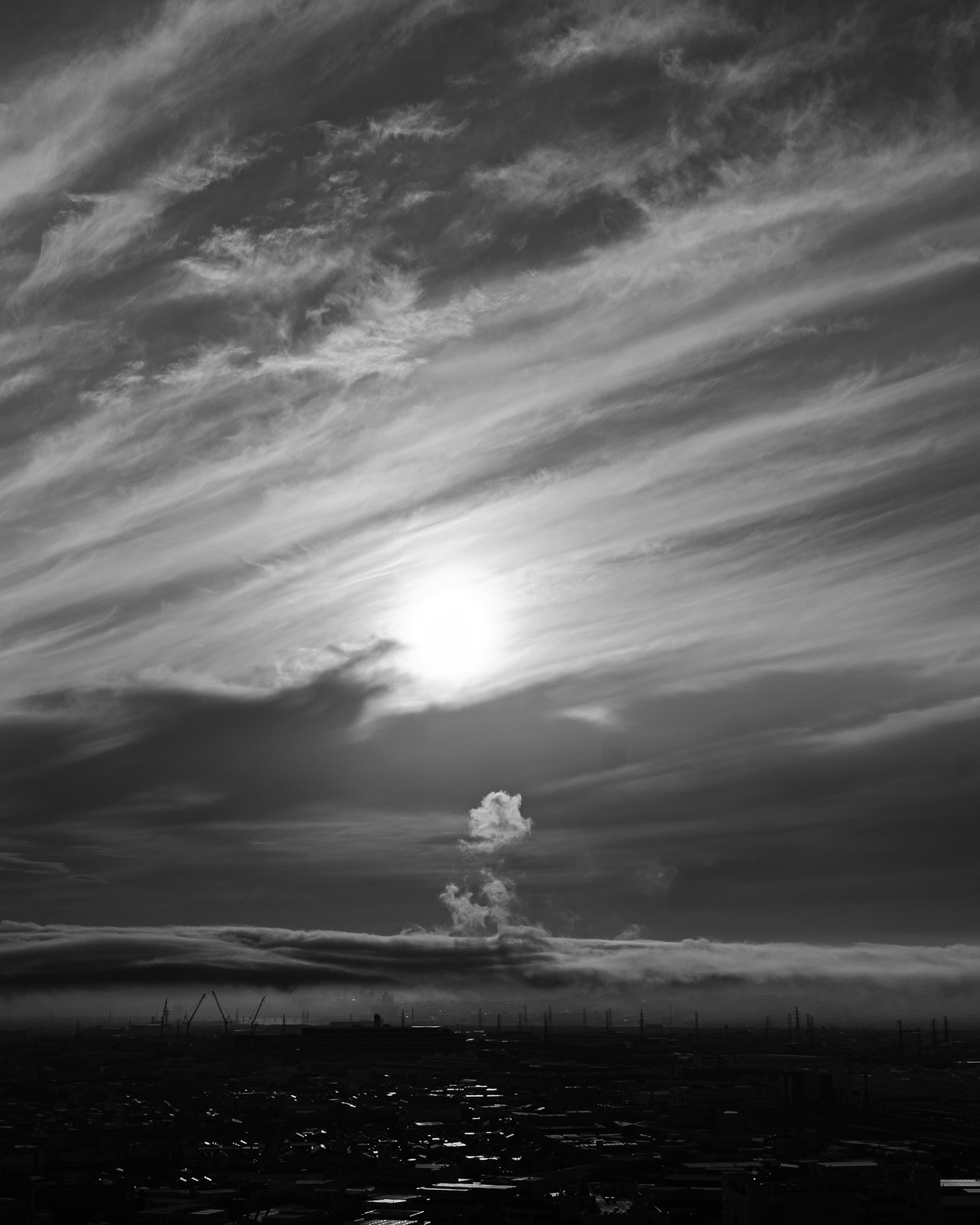 Silhouette of the sun against a backdrop of clouds in black and white sky