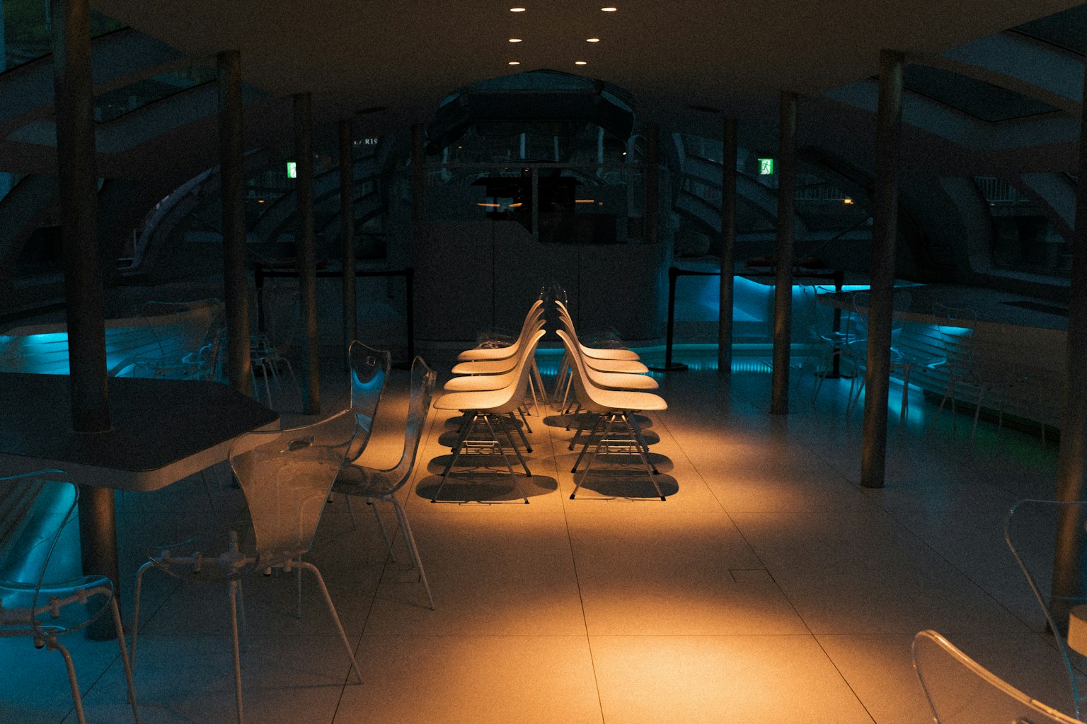 Espacio interior moderno con iluminación tenue que presenta una larga mesa y sillas transparentes