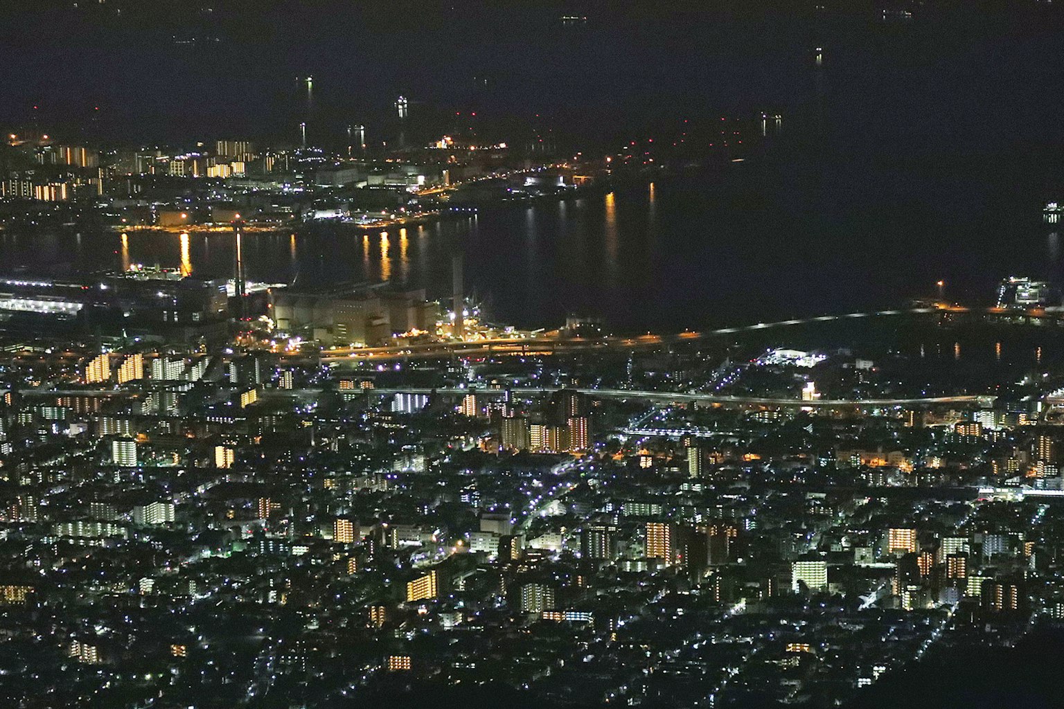 Vue aérienne d'une ville la nuit avec un port et un pont