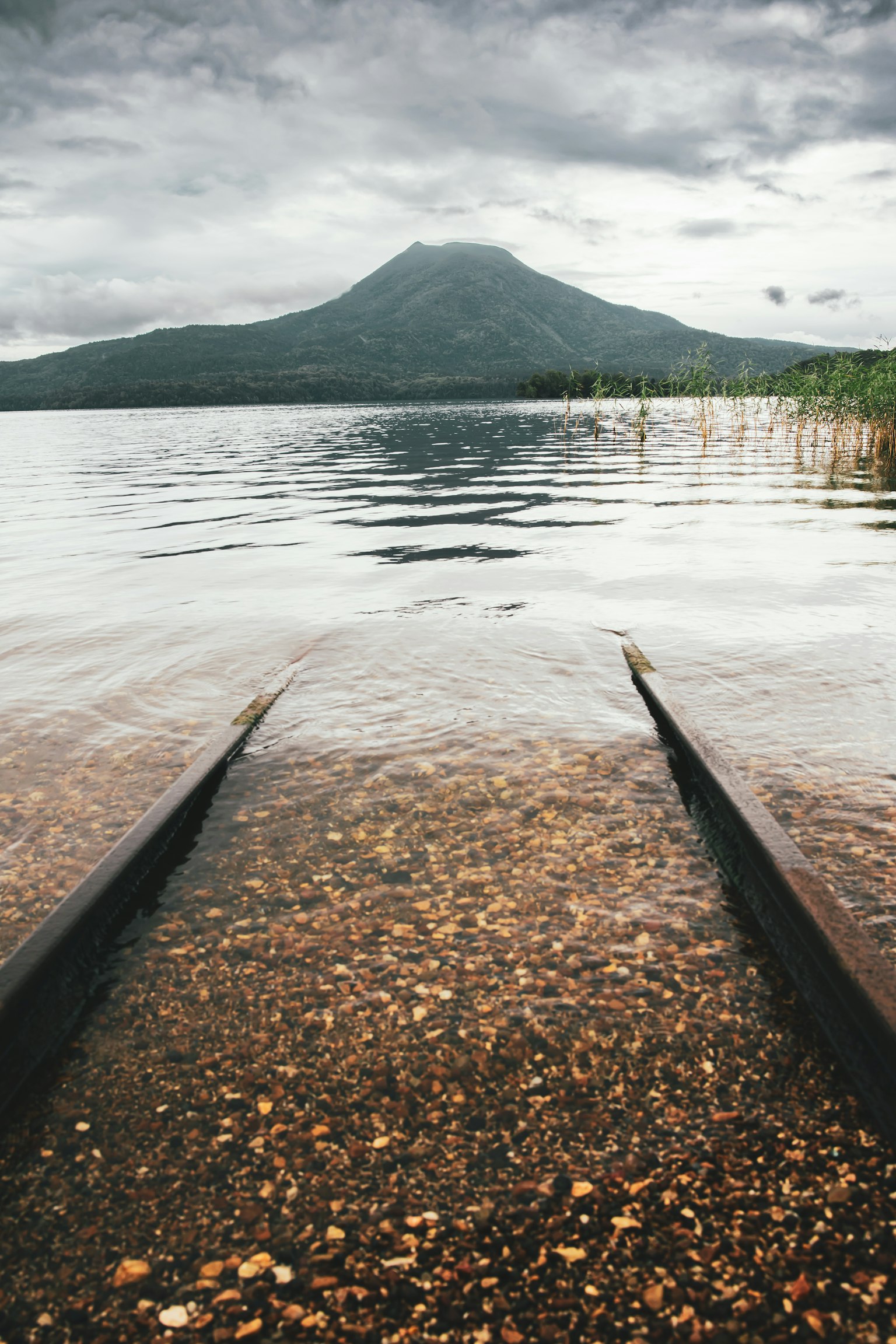 宁静的湖景，船坡通向水面，背景有山