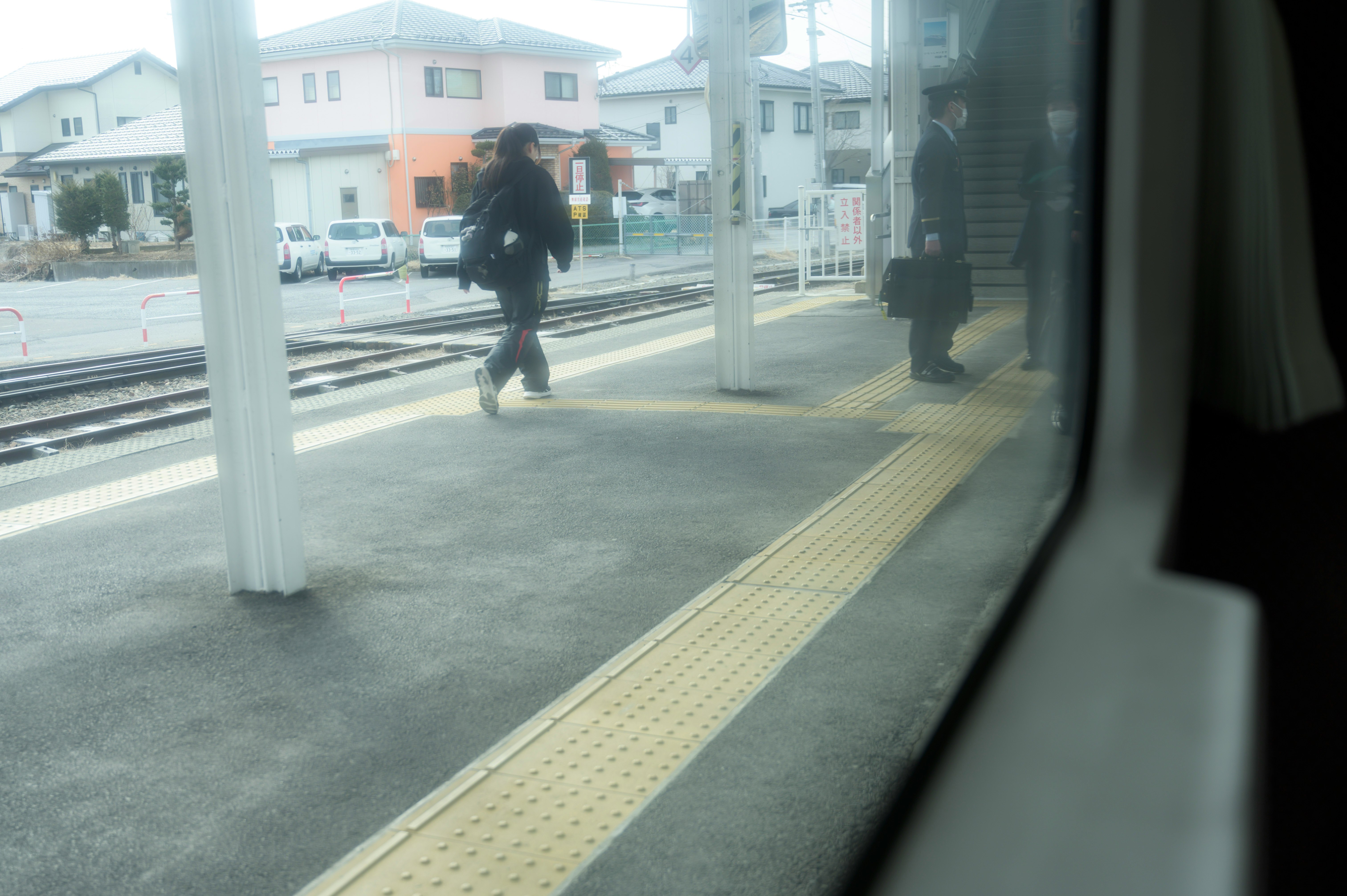 駅のホームで線路を走る列車と人